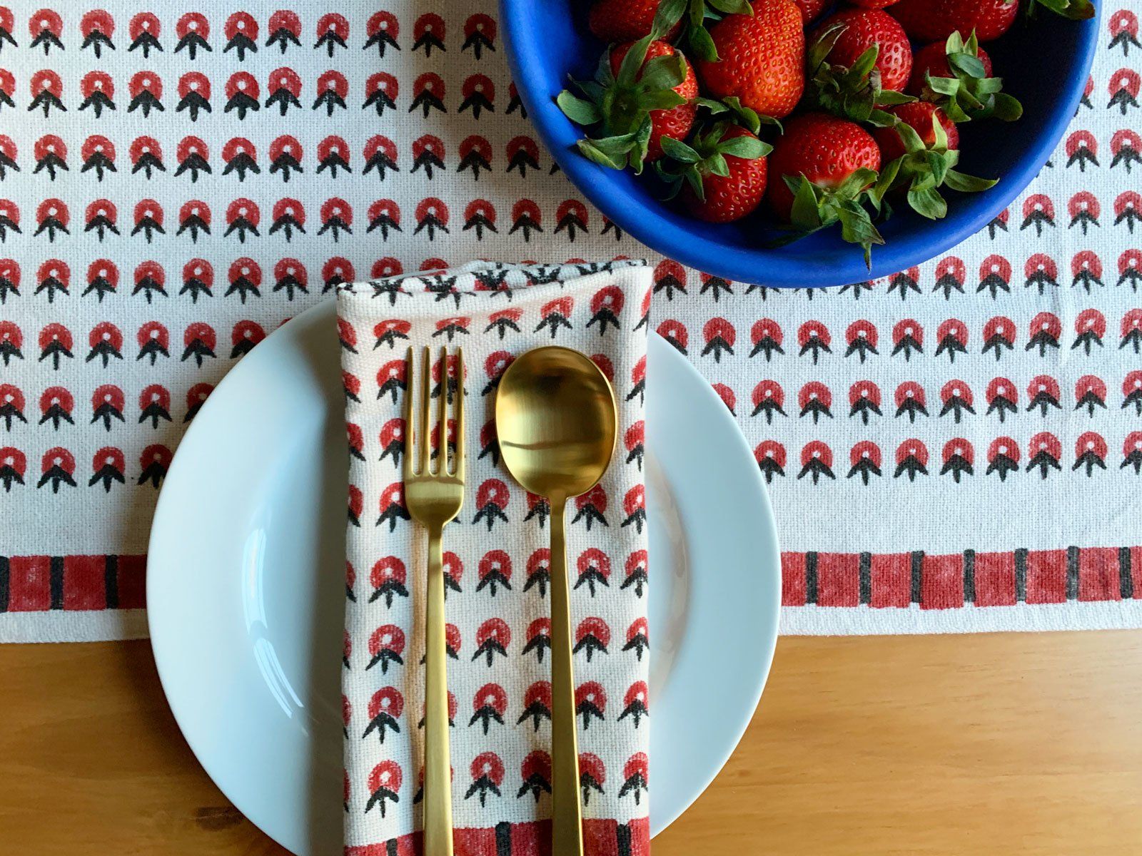 SUNDAY/MONDAY's POPPY table linens featuring a summery floral inspired pattern. Red and white cloth napkins and a table runner.