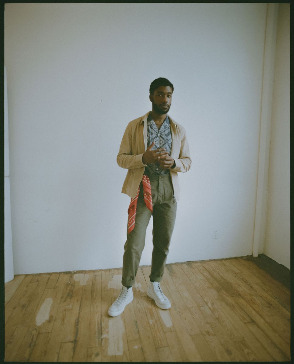 Film photo of a Black male model wearing a red bandana tied a belt loop. 